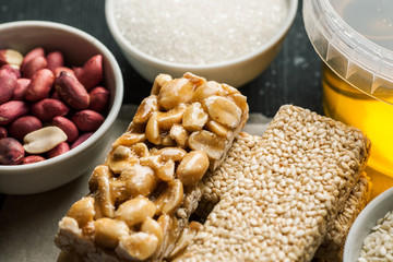 Peanut and sesame brittle with honey jar and raw ingredients in the white ceramic bowls
