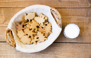 Basket with biscuit and glass of milk on wooden background