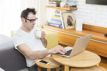 Fototapeta na wymiar Man sitting in his living room and working on laptop.