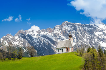 Fototapeta na wymiar Church of Dienten am Hochkönig in front of a snowy mountain range, Pinzgau, Salzburg, Austria