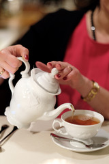 A woman pours tea into a cup.