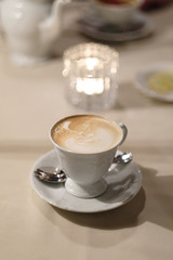 A cup of cappuccino coffee on a dessert table.