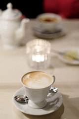 A cup of cappuccino coffee on a dessert table.