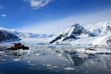 Leopard seal resting on ice floe, watched by tourists, Antarctic peninsula
