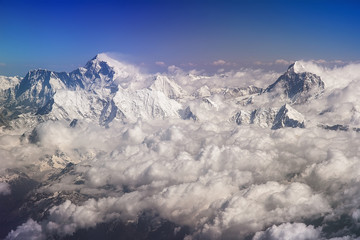 Himalaya mountains summits, Everest and Lhotse on the left, Mt. Makalu on the right, with snow flags and clouds, view from plane