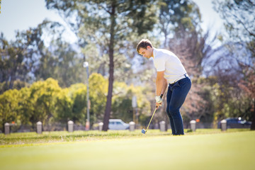 Close up view of a golfer playing a chip shot on a golf course in south africa with back light.