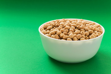 Raw chickpea or garbanzo bean in a bowl on green background