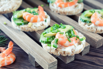 Rice cakes with sliced avocado cucumber shrimp and cream cheese.  Fresh parsley and rosemary. Vegetarian, vegan concept. Shallow depth of field. Coloring and processing photo.