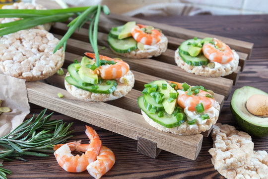 Rice cakes with sliced avocado cucumber shrimp and cream cheese.  Fresh parsley and rosemary. Vegetarian, vegan concept. Shallow depth of field. Coloring and processing photo.