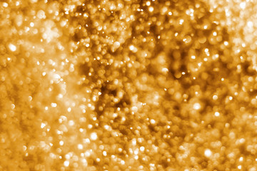 Golden abstract sparkles or glitter lights. Festive gold background. Defocused circles bokeh or particles. Template for design