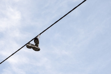sneakers hanging from electrical wire against a blue sky