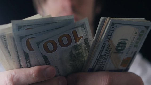 Close-up of a businessman's hands counting hundred dollar bills