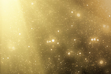 Golden rays and sparkles or glitter lights. Merry Christmas festive gold background.defocused circle bokeh or particles