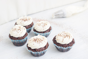 Chocolate cupcakes on white wood background, copy space