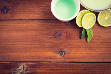 close up of body lotion, cream and limes on wood