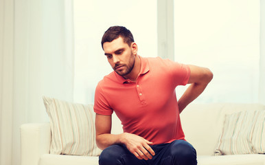 unhappy man suffering from backache at home