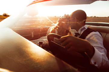 Young loving couple in a cabriolet at sunset