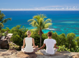 Fototapeta premium smiling couple making yoga exercises outdoors