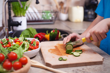 Child hands slicing a cucumber for a salad