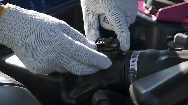 Professional mechanic sets the oxygen sensor to the air filter under the car hood