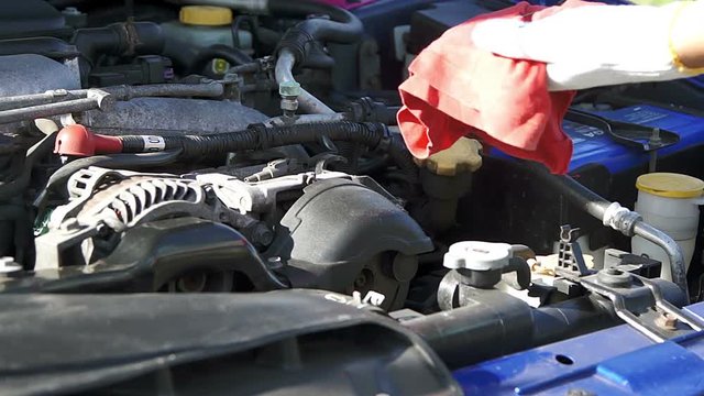 Repair man checking car engine oil under open hood