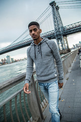 A young, black man walks along NYC's East River - Autumn 2016