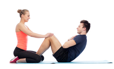 Obraz premium happy sportive man and woman doing sit-ups