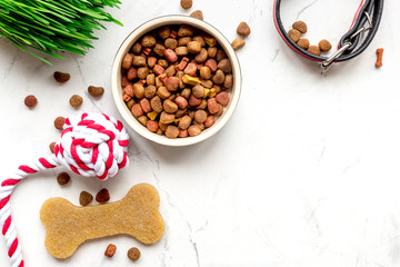 dry dog food in bowl on stone background top view