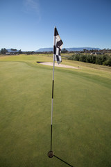 Obraz premium Wide angle view of a flag in the hole on the green of a golf course