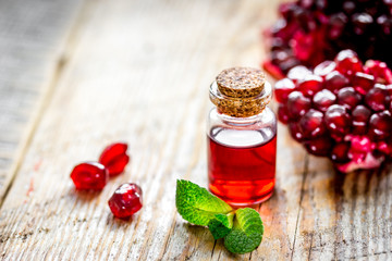 sliced pomegranate and extract in glass on wooden background
