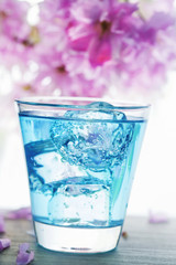 Blue drink with ice and pink flowers in the background