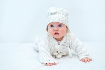 The baby is dressed in white and on a white background lifted on his hands.