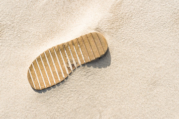 Shoe sole buried in the sand. Wavy sand on the beach. Abstract.