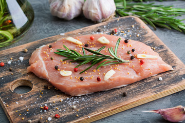Piece of raw pork meat with ingredients on wooden plank