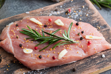 Piece of raw pork meat with ingredients on wooden plank