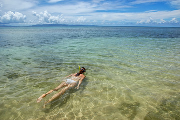 Fototapeta na wymiar Young woman snorkeling in clear water on Taveuni Island, Fiji