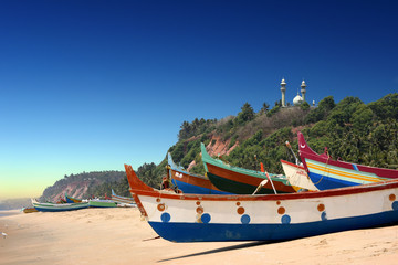 colourful fishermen boats in fron of Varkala South Cliff with mosque on top, Kerala, India
