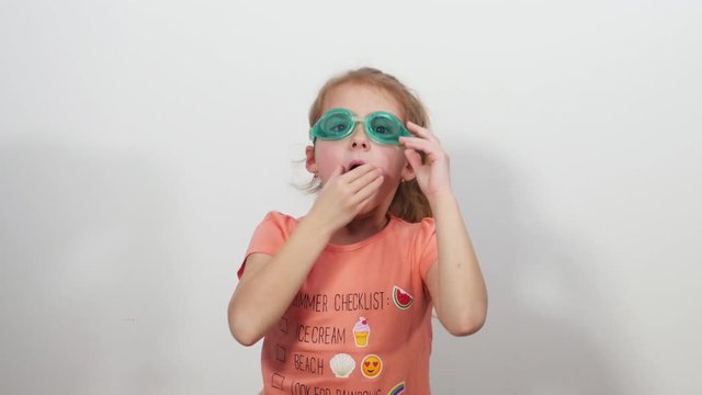 Little funny girl with glasses for swimming dives and emerges with shell. 