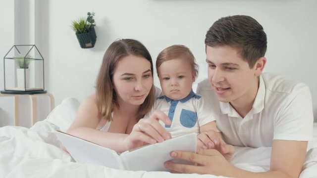 happy loving family. pretty young mother and ded reading a book to her daughters
