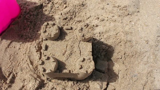 Making a sandcastle and then destroying it with a child's foot
