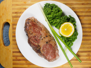 Braised beef brisket on a plate with kale and green onion