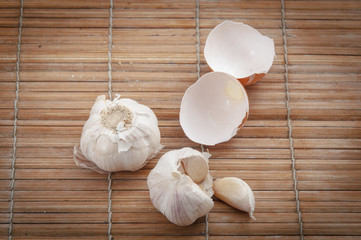 Broken brown chicken egg shell with garlic on wooden surface cover