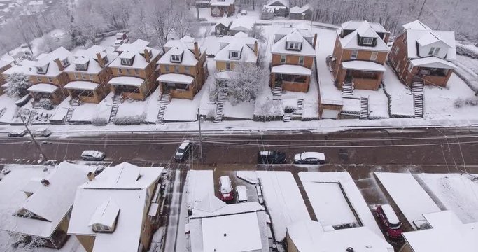 A slowly moving backwards aerial winter view of a typical Western Pennsylvania residential neighborhood during a snowstorm.	 	