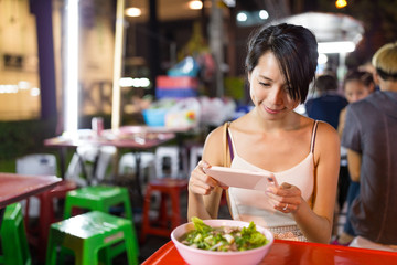 Woman taking photo on the bowl in night market of bangkok