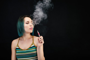 Obraz premium Jeune femme vape une cigarette électronique