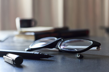 glasses and book on wooden table with soft-focus in the background. over sunlight