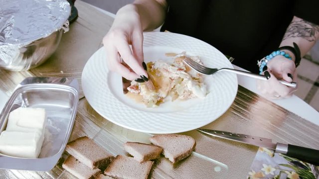 Manicured female hands with piece of bread in scrambled eggs on a plate