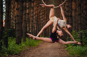 Two beautiful and slim gymnasts doing difficult exercises on aerial silk in the forest

two beautiful and slim gymnasts doing difficult exercises on aerial ring