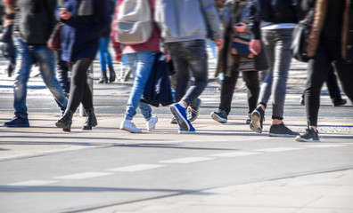 Many pedestrians cross a street in a city