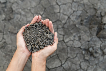 Hand holding soil over dry and crack soil because no water long time at here.